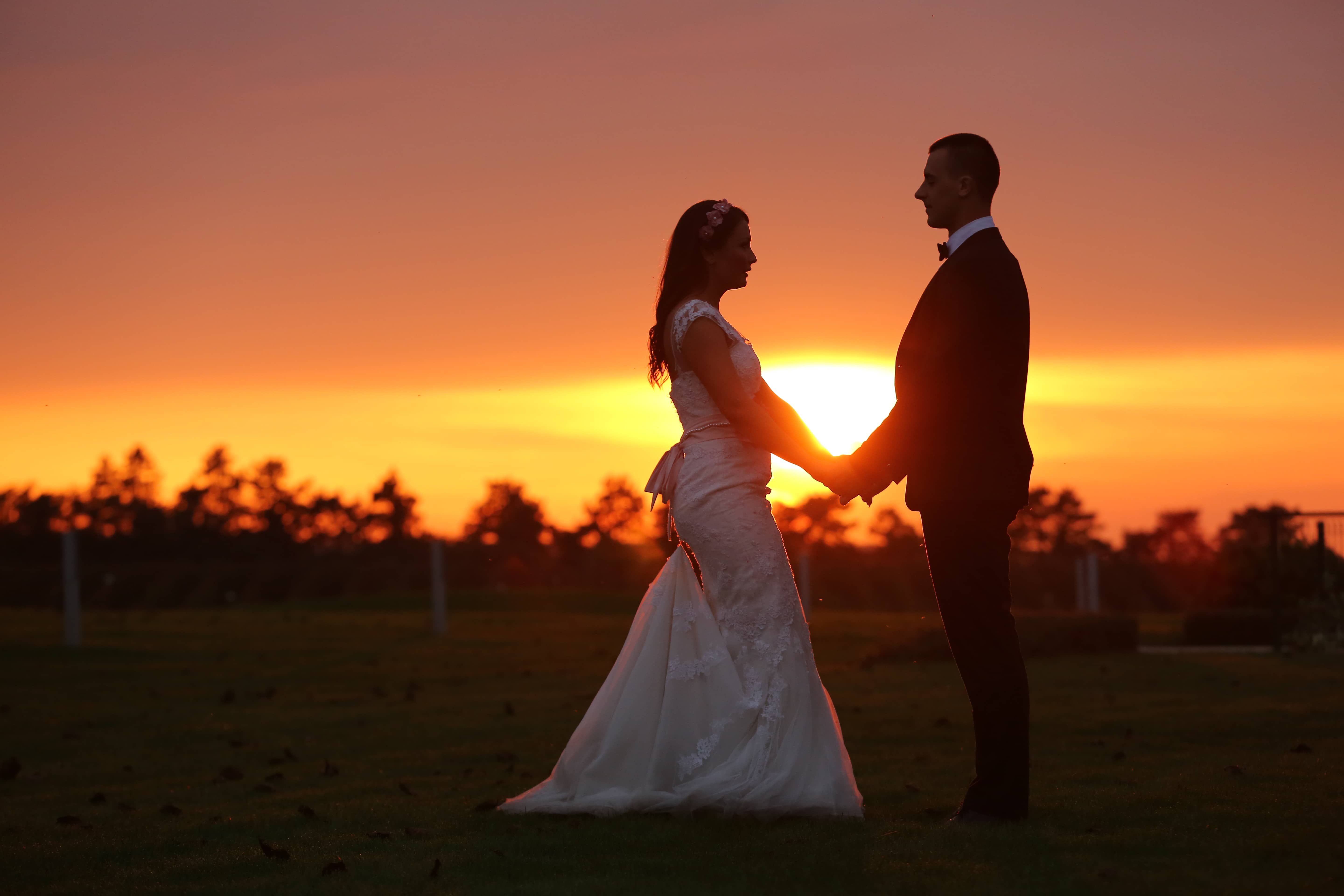 Bride and groom holding hands at sunset
